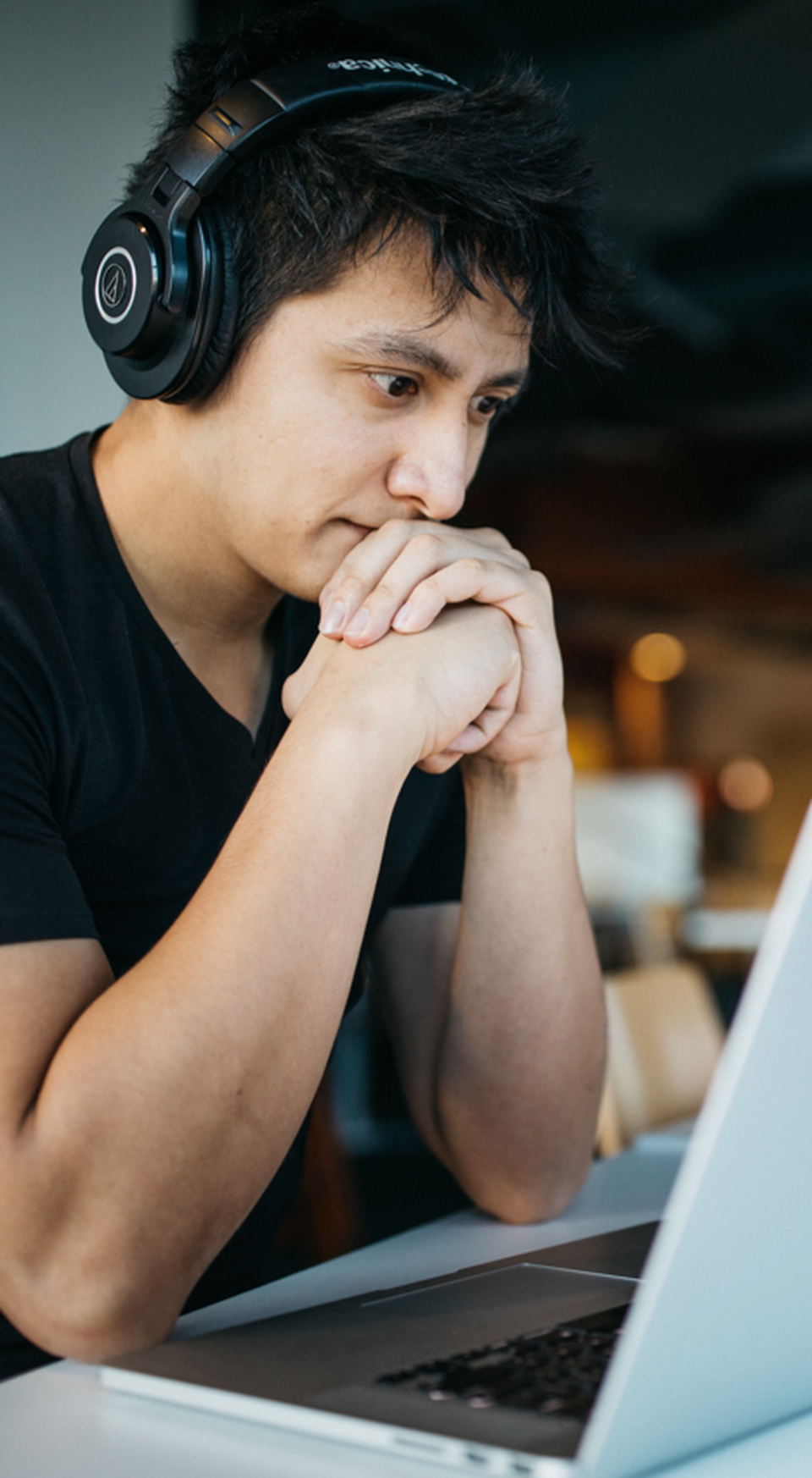 A men with headphones looking worried to the laptop screen